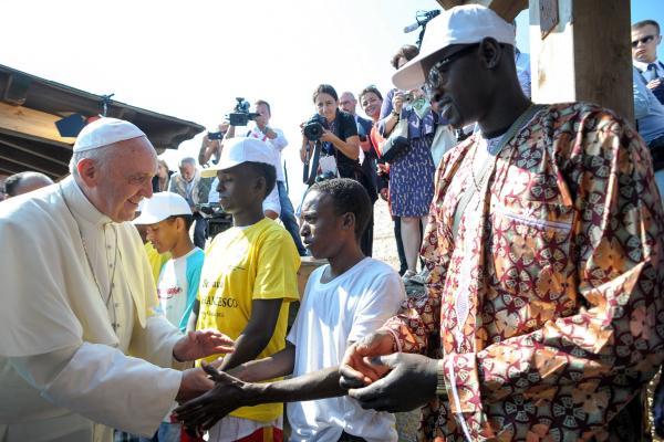 Pope greets migrants.